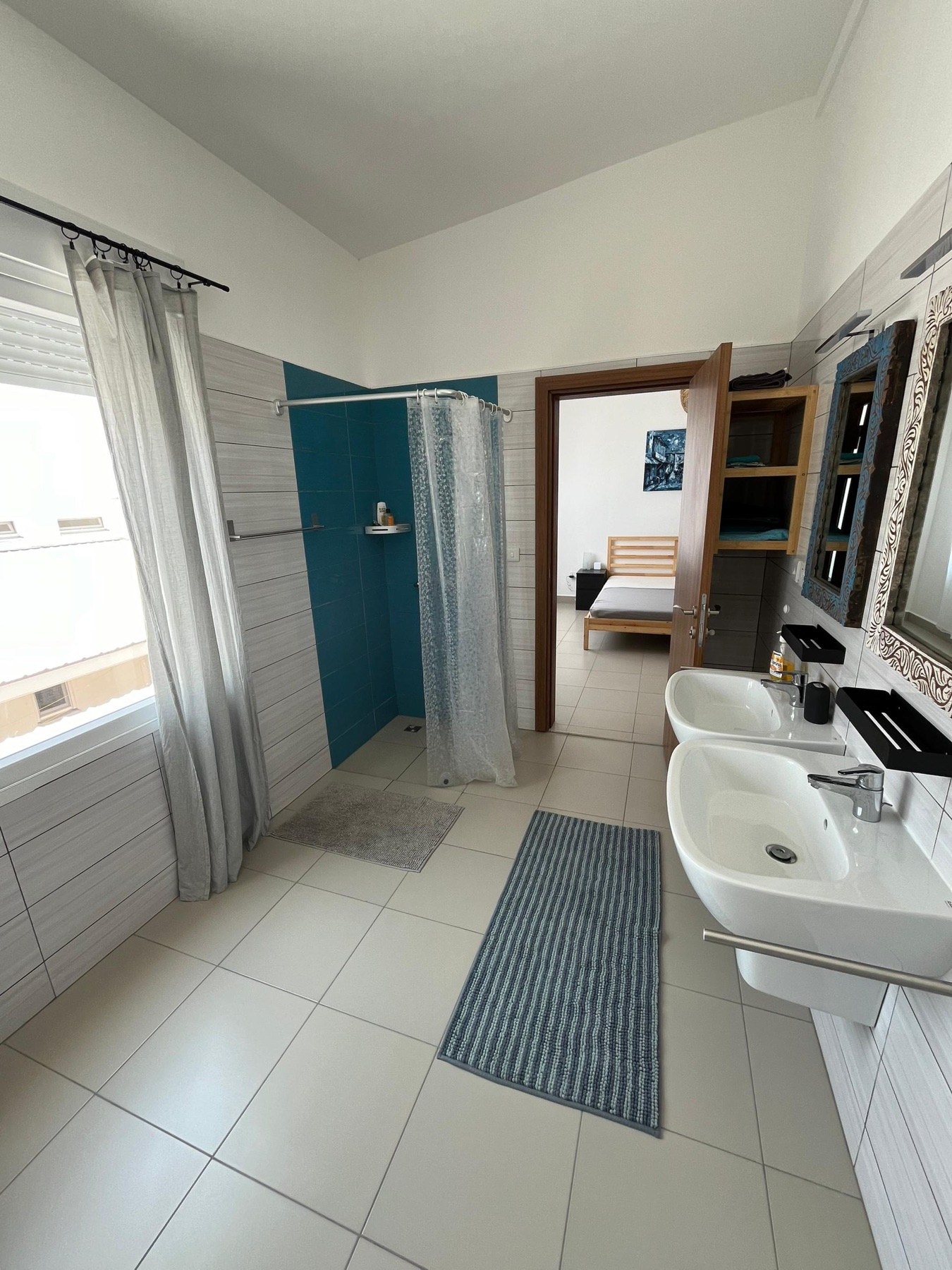 Large bright bathroom with two basins and shower